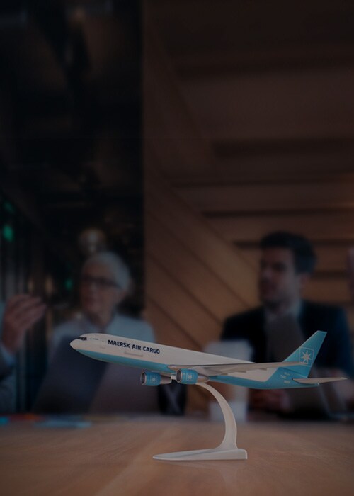 Airplane dummy on a table will multiple people in the background