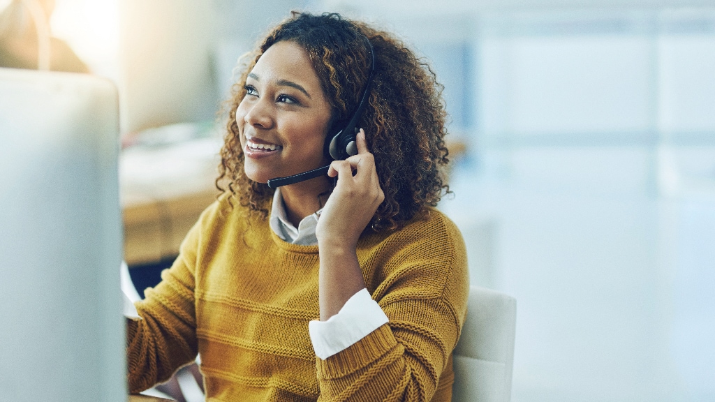 Female wearing a yellow shirt smiling while working in front of desktop