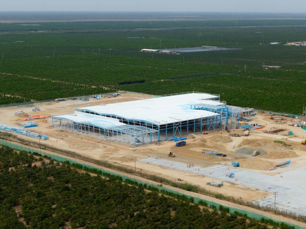 Aerial view of a large building under construction, showcasing scaffolding and construction equipment surrounding the site.