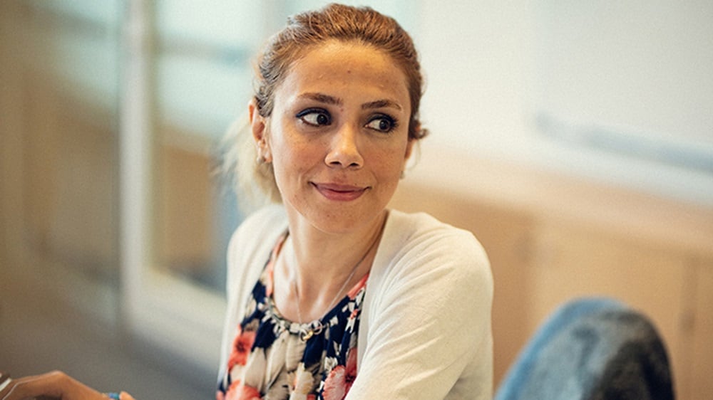 一位女性 UX 设计人员坐在工作站,微笑着看向她的左侧。