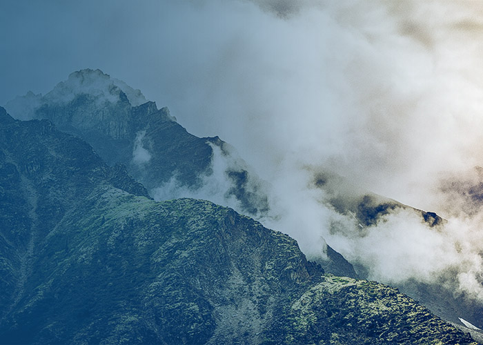 Misty mountain ridge with rocky peaks partially covered in clouds and fog