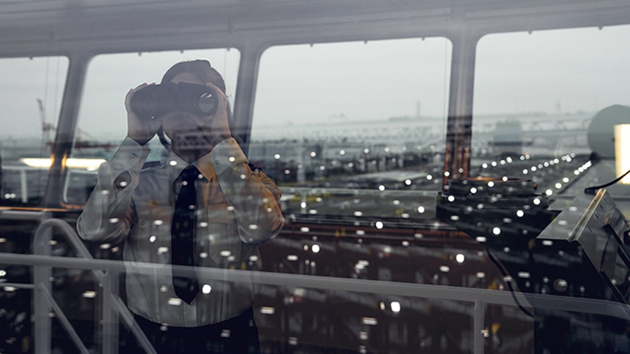 Business professional using binoculars through window