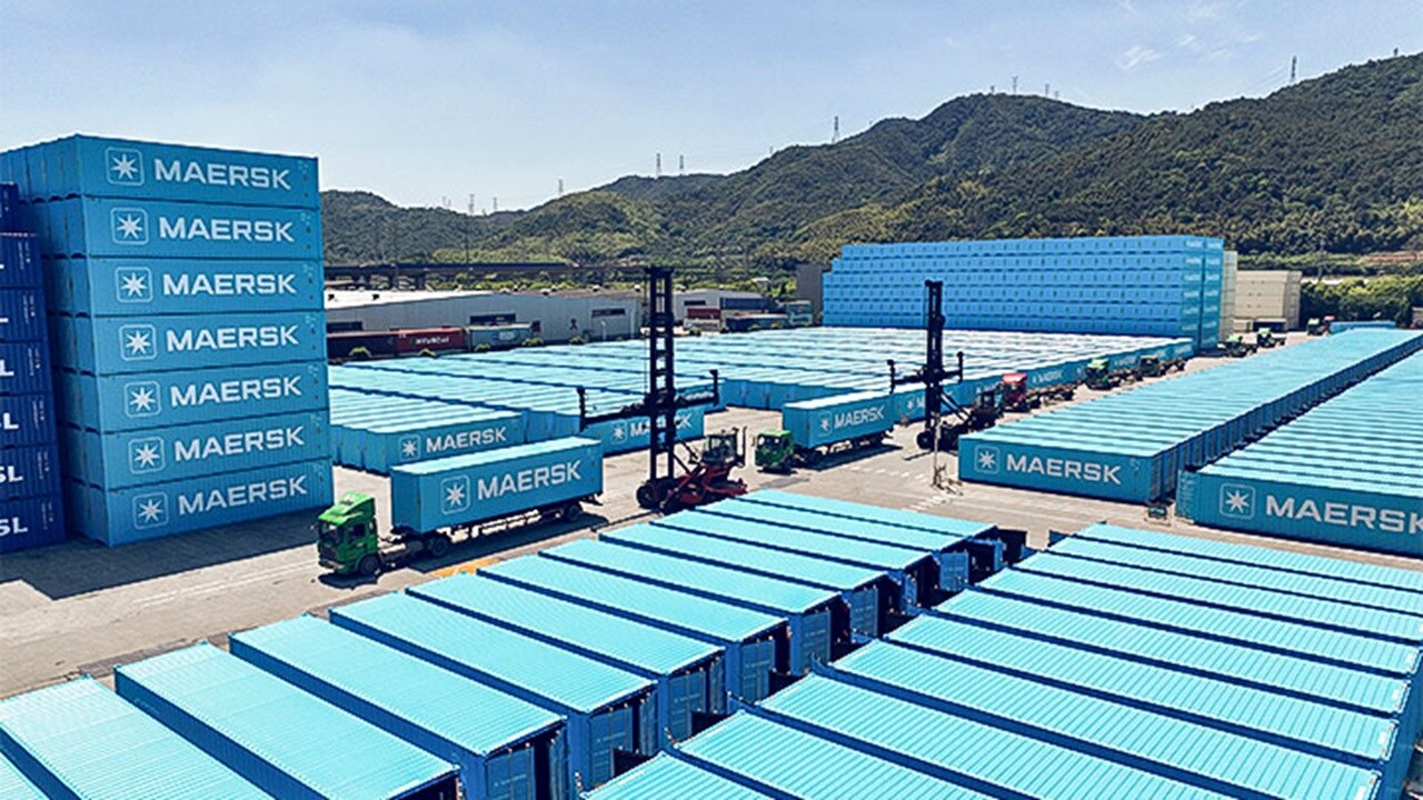 A large Maersk logistics facility with rows of shipping containers, trucks, and container-handling equipment