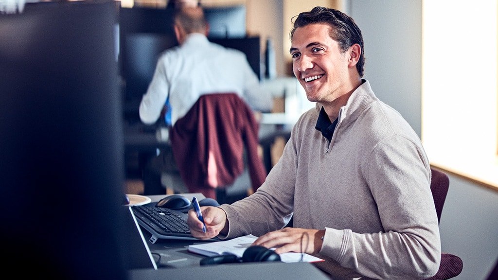 Man smiling at desk with pen and paper