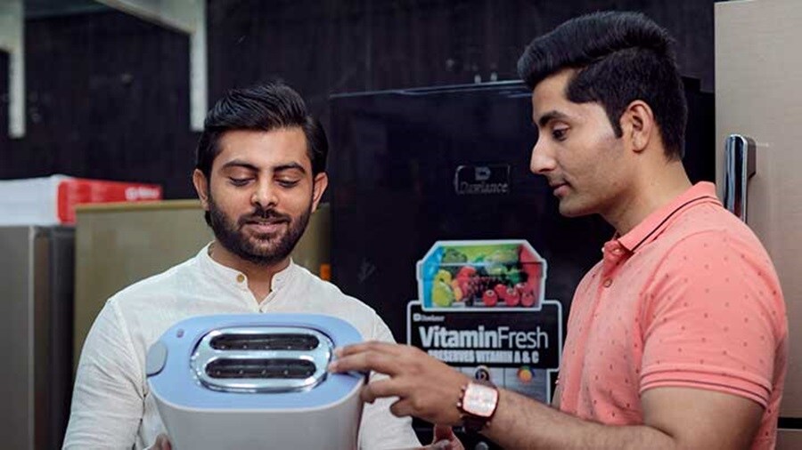 customers holding a toaster at an electronic store