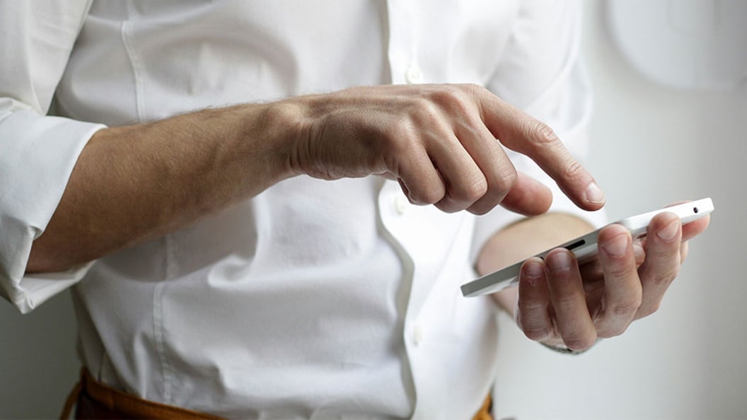 Close-up of a person in a white shirt holding and interacting with a smartphone