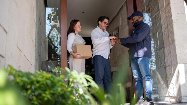 Young couple receiving a package from the delivery person at their front door