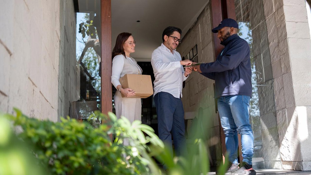 Young couple receiving a package from the delivery person at their front door