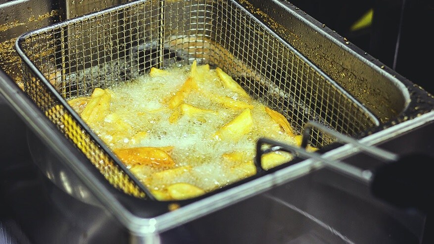 A kitchen frier frying French fries with oil 