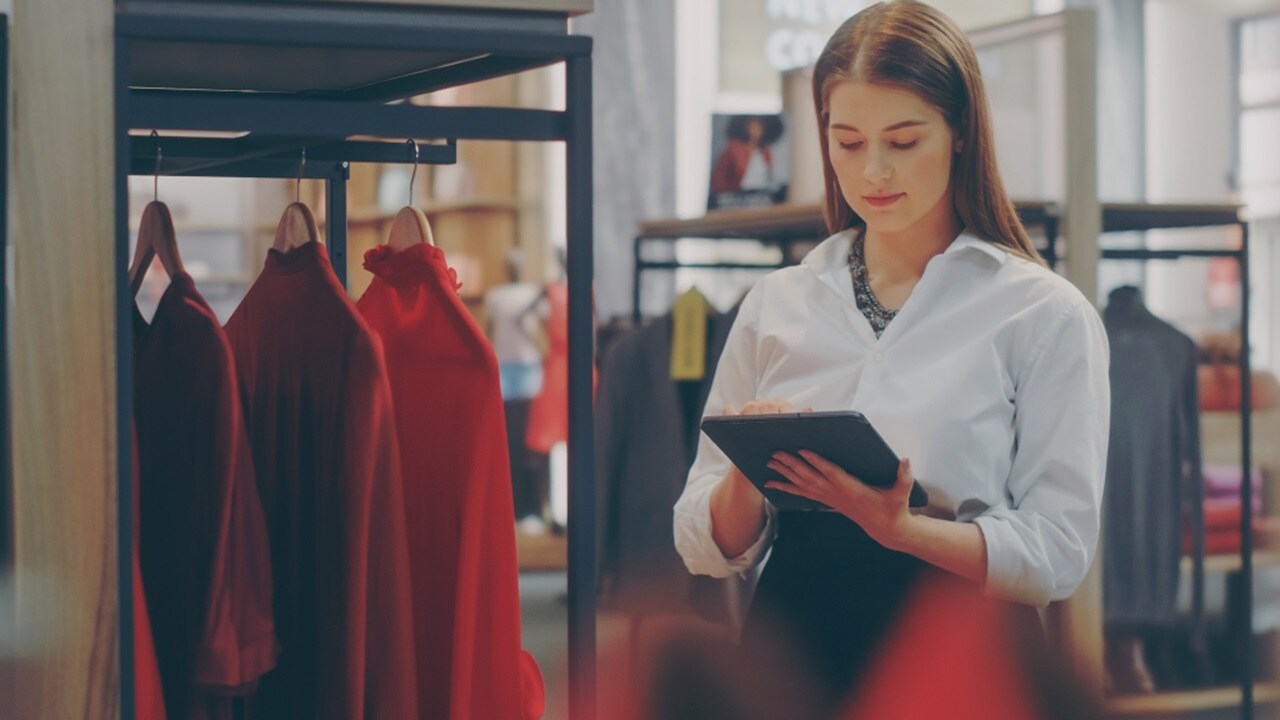 A woman in a retail clothing store looking at data on their tablet