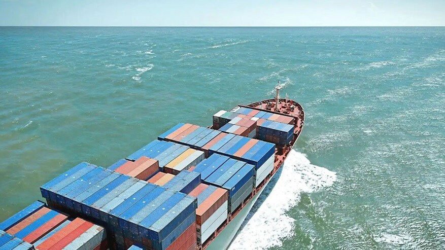 A large vessel loaded with multiple containers in the middle of a vast ocean.