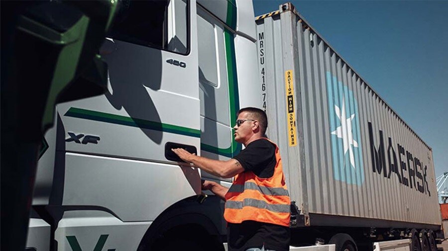 A man opening the door of Maersk transporting truck