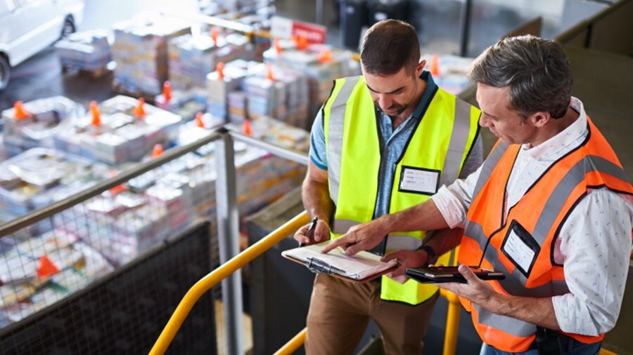 Two men checking logs at warehouse