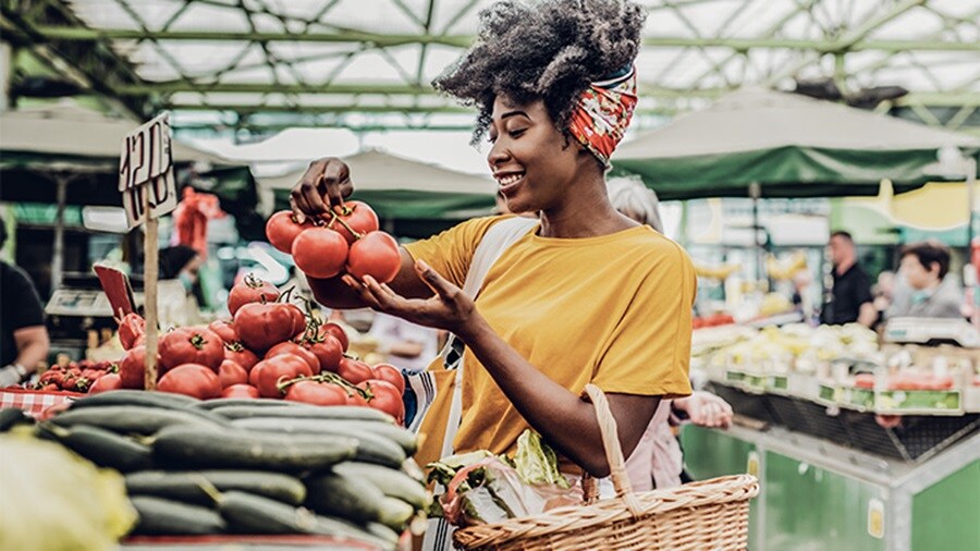 Young African woman buying tomatoes at the market