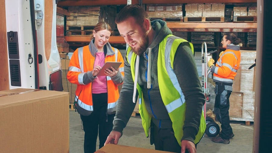 Multiple people with protective gear on working in a warehouse
