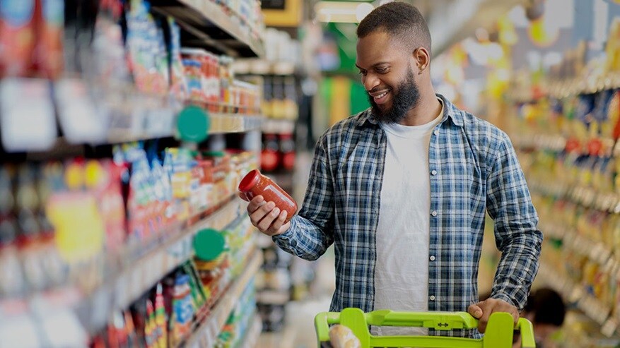 A Nigerian man with a trolley checking out fast-moving consumer goods in a supermarket. 