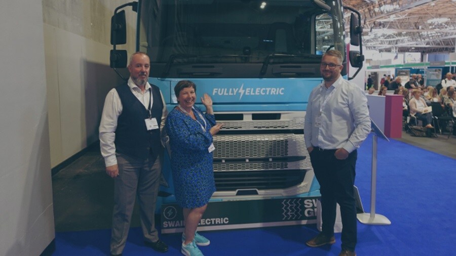 Two male and a female standing in front of a blue truck