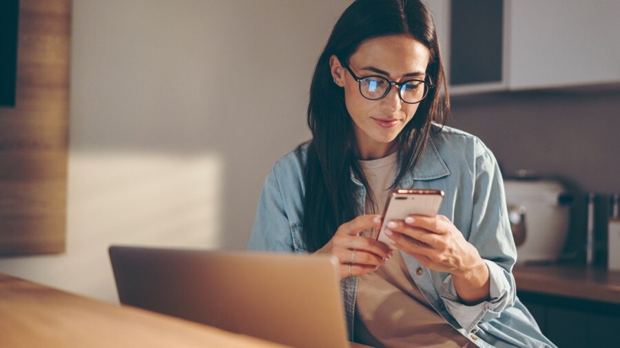 Woman using her phone with laptop open