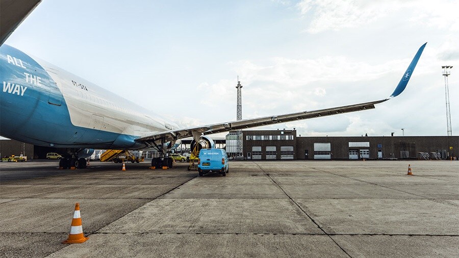 Large commercial airplane on tarmac with ground support vehicles nearby.