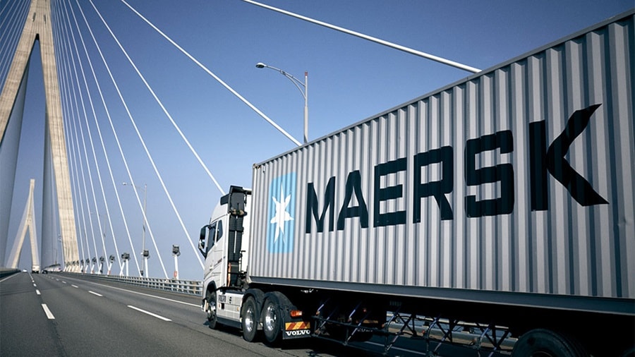 Truck with a Maersk container driving across a bridge.