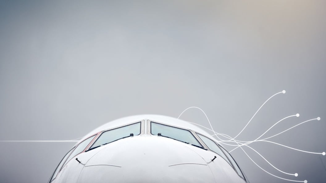 A commercial airplane soaring through the sky with a single cloud in the background.