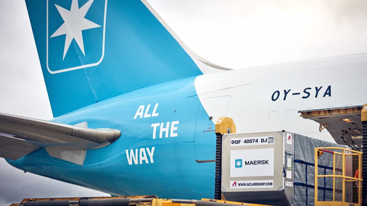 A large blue airplane with a cargo box mounted on top, ready for transport at an airport.