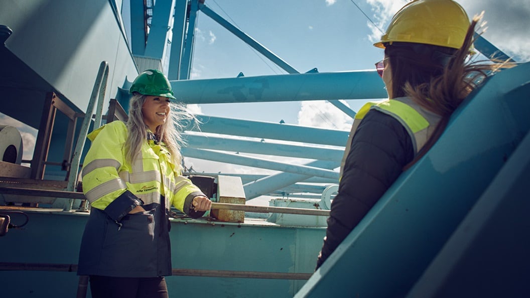 Two people standing on a crane in a terminal