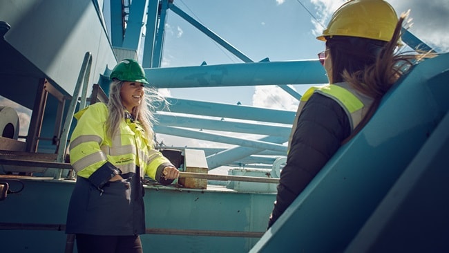 Two people standing on a crane in a terminal