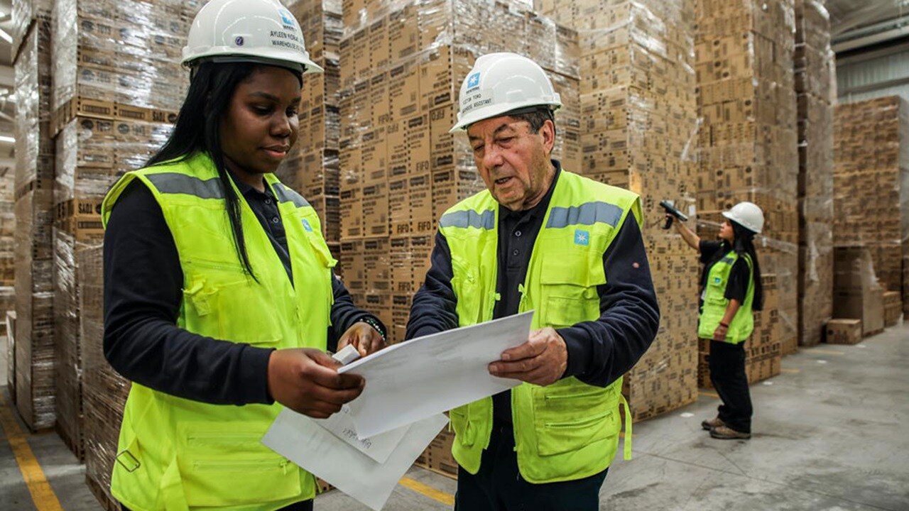Two Maersk warehousing employees looking at customs documentation at a warehouse