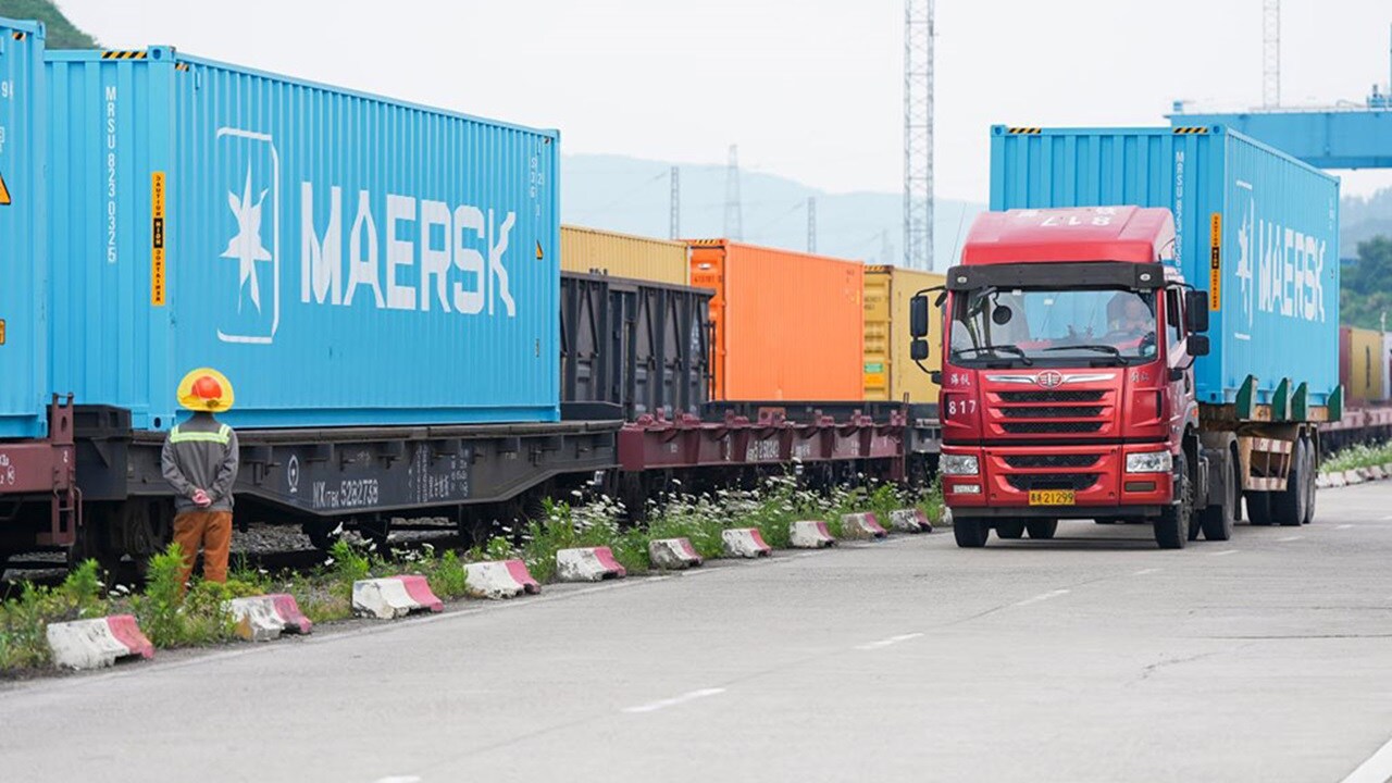Maersk containers loaded on a freight rail and truck for intermodal transport at terminal