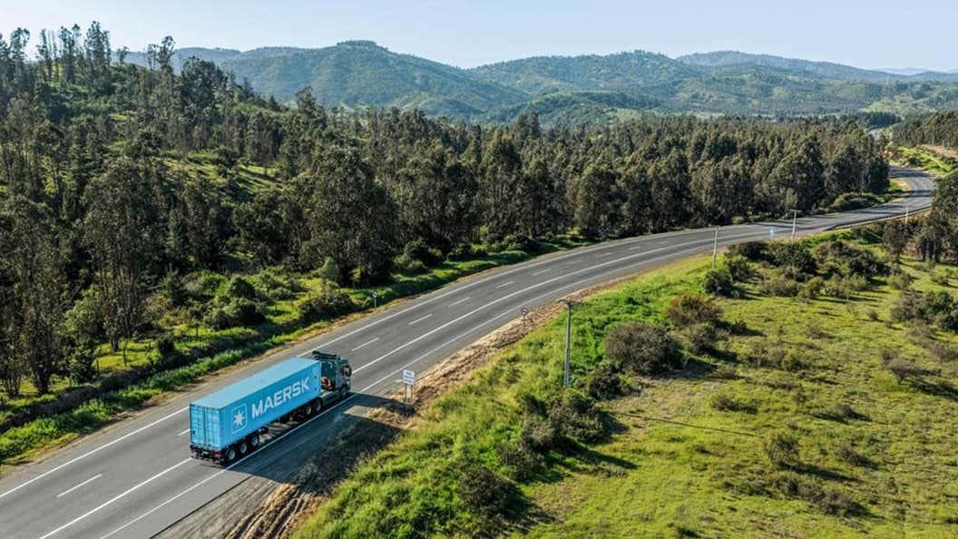 Maersk transport truck driving on a highway through a green forest landscape, representing North American ground freight