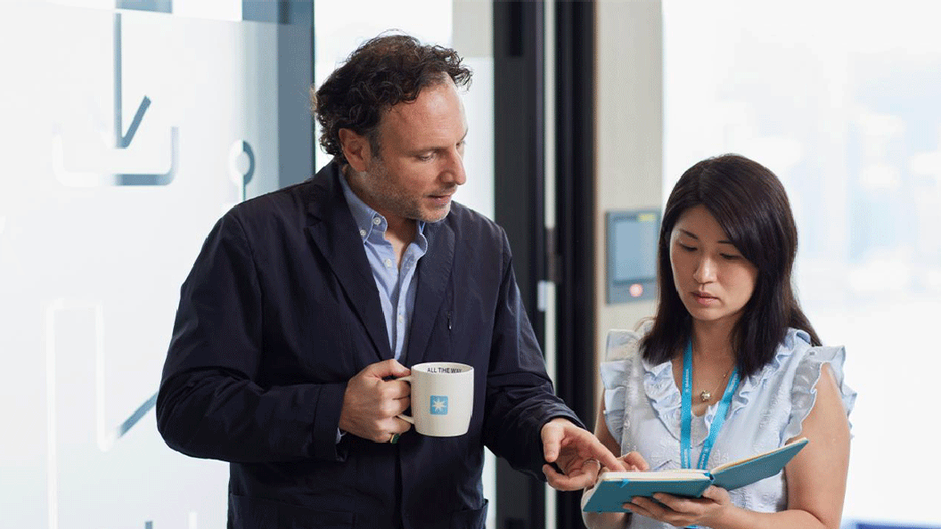  A man and woman stand together, smiling, in front of a large coffee cup on a table.