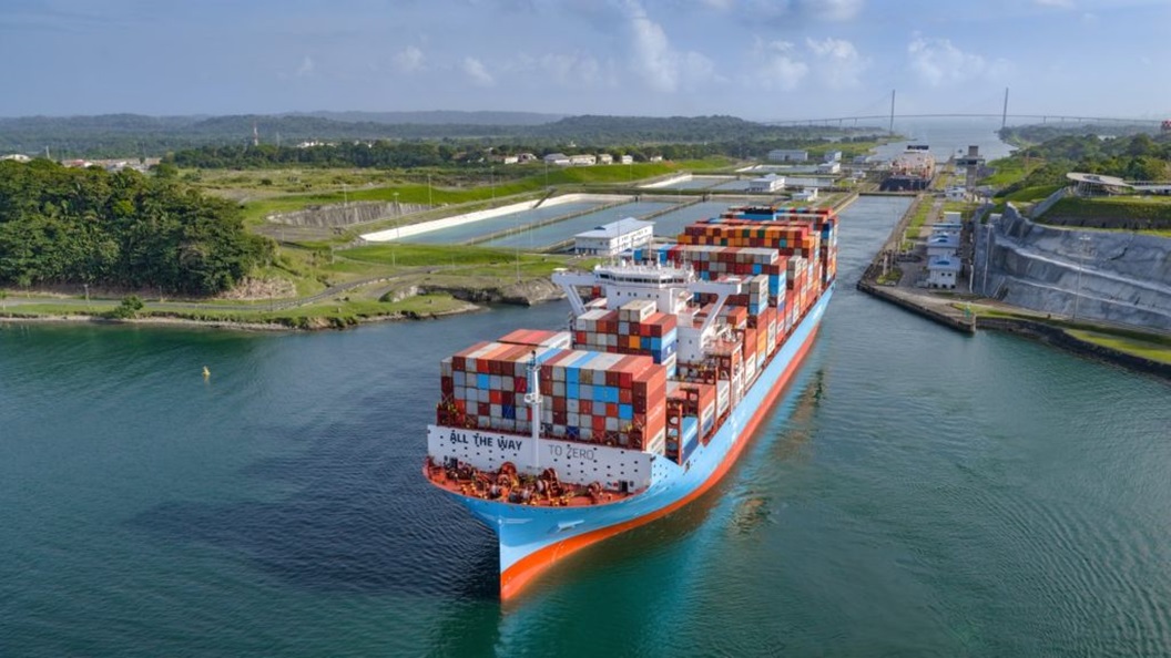 Aerial view of the container vessel Tangier Maersk transiting the Agua Clara Locks in the Panama Canal, carrying stacked shipping containers through the waterway.