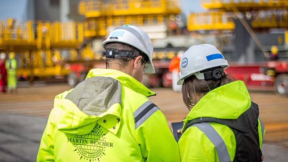 现场的 Martin Bencher 工人戴着防护装备查看手机。